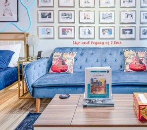 Une pièce avec un canapé bleu, une table basse, des tableaux encadrés au mur et un livre intitulé « Bienvenue ».