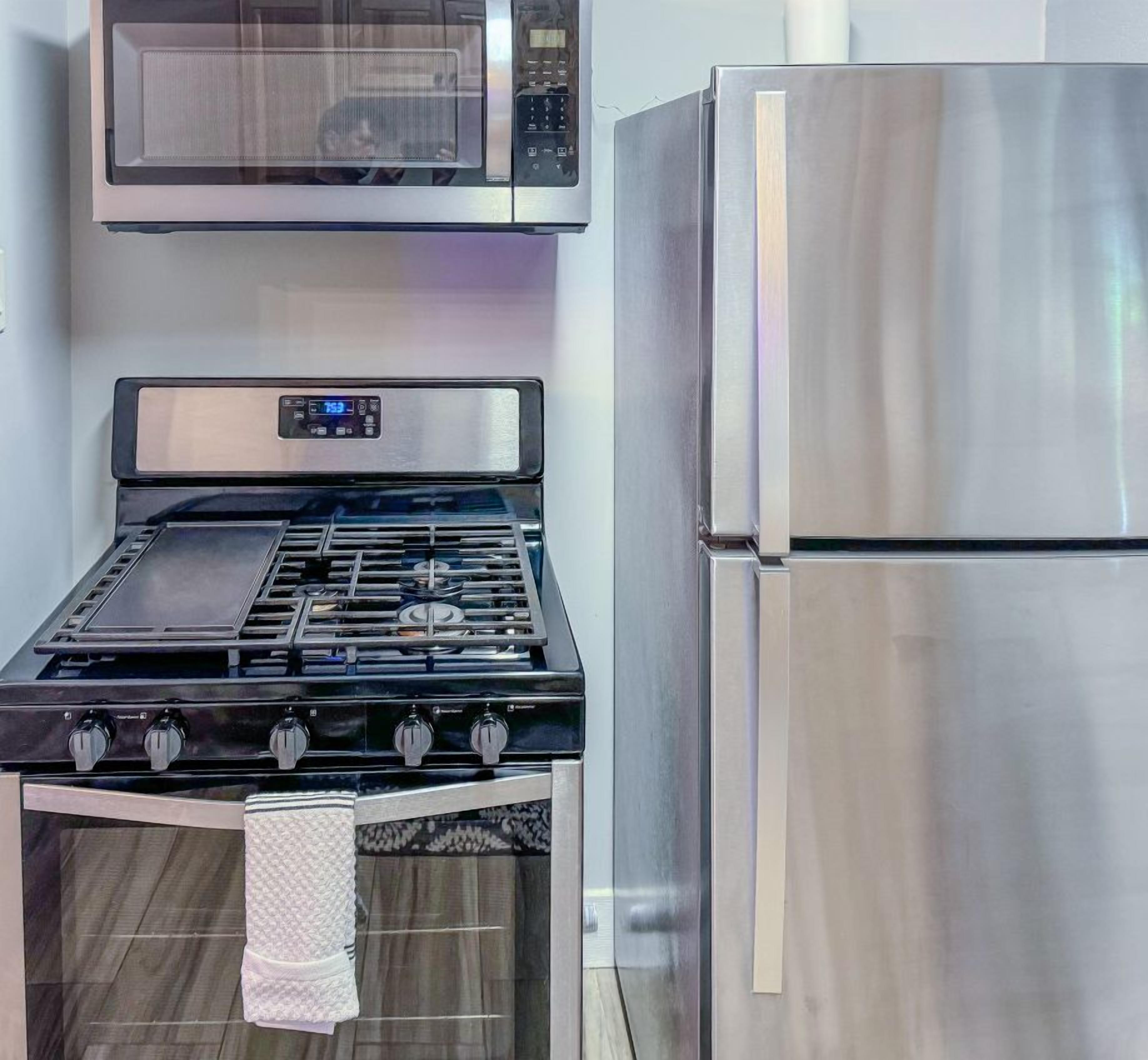 A kitchen with a stainless steel stove, microwave, and refrigerator.