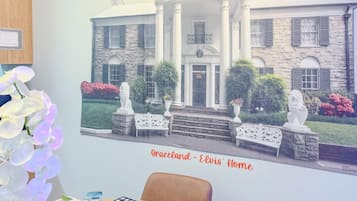 Una habitación con un cuadro enmarco de un edificio que dice 'Graceland - Casa de Elvis' y una mesa de comedor con sillas.