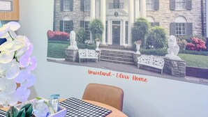 Une pièce dont un mur est décoré d’une fresque représentant un grand et imposant bâtiment, avec l’inscription « Graceland – la maison d’Elvis ».