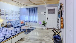 Une chambre à coucher moderne avec un lit, un canapé, une table basse et un mur décoré de tableaux encadrés.