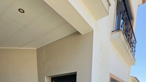 A modern building with a dark entrance door, a small step leading to the entrance, and a concrete pathway. - Vila Darte Alojamento Local (Vila de Rei)