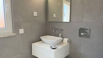Un baño moderno con un tocador blanco, un espejo grande y un inodoro.