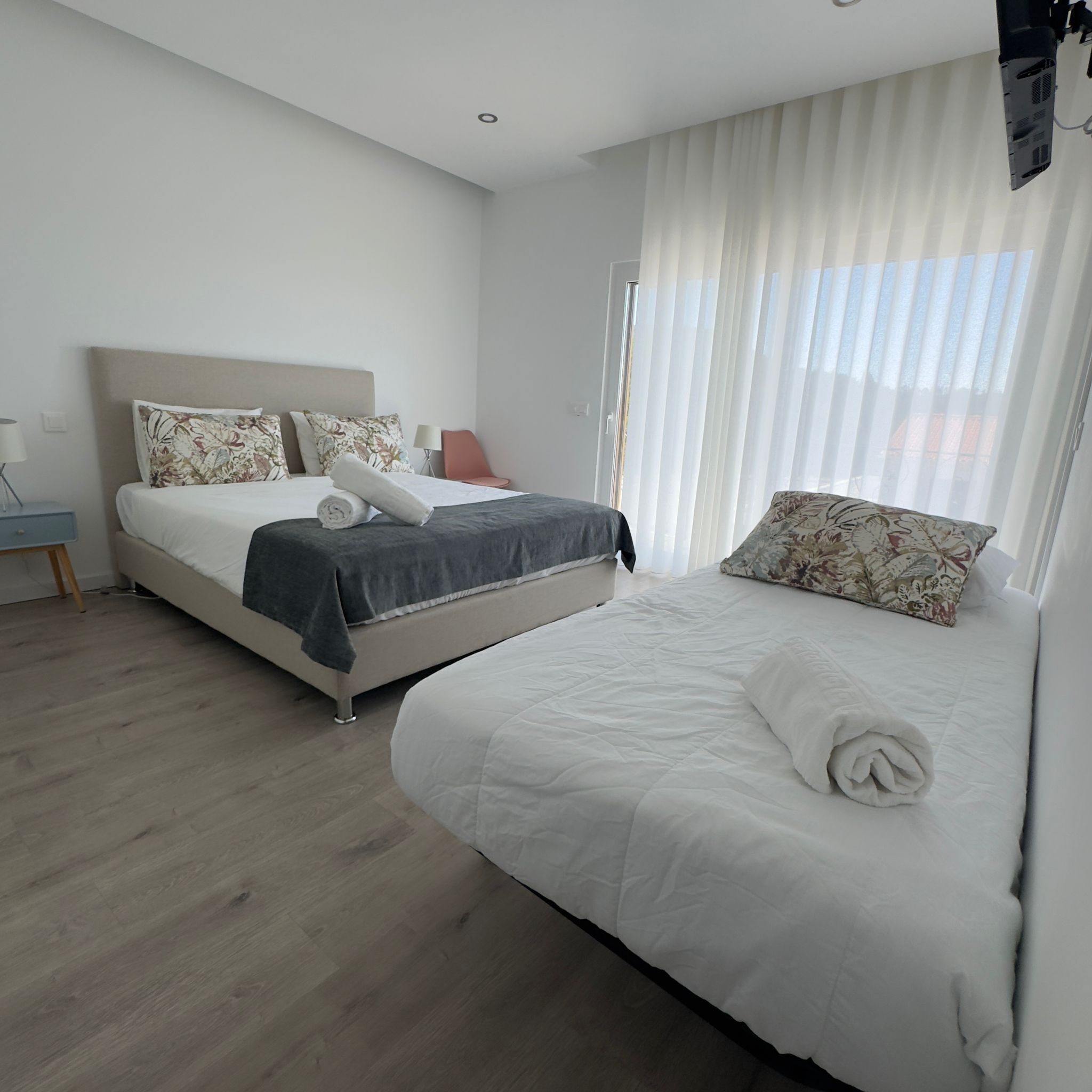 Una habitación de hotel moderna con una cama grande, una cama más pequeña y un escritorio.