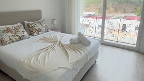 A modern bedroom with a large bed, a view of a balcony, and a wooden floor. - Vila Darte Alojamento Local (Vila de Rei)