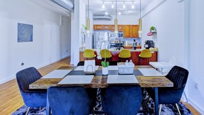A modern dining area with a wooden table, blue chairs, and a kitchen in the background. - Modern Spacious Loft in Downtown w/ free parking (Memphis)