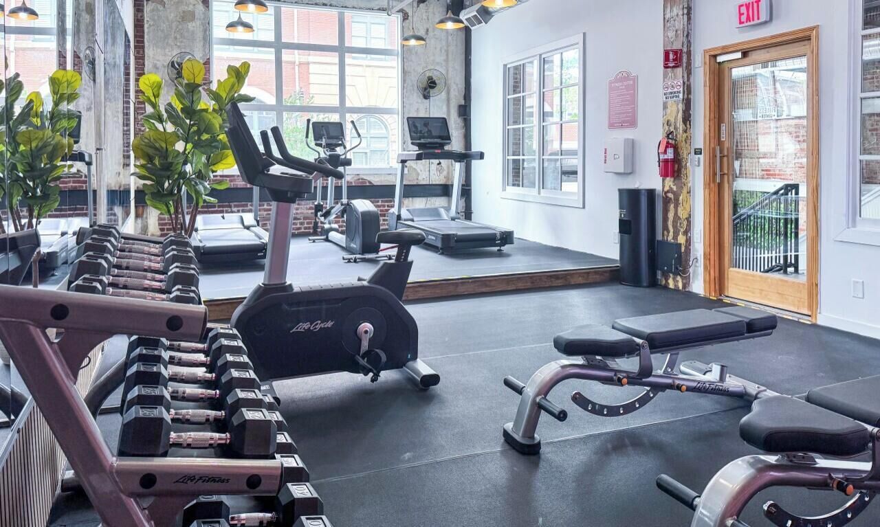 Un gimnasio con equipo de ejercicio, una cinta de correr y un espejo grande.
