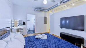 A modern hotel room with a bed, a vanity with lights, a television, and a ceiling fan. - BRAND NEW Modern Spacious Loft in Downtown with free parking (Memphis)
