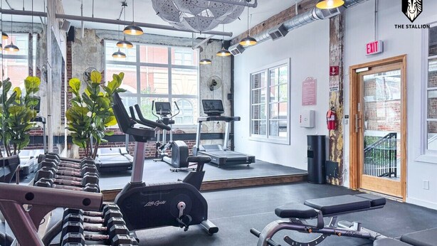 A gym with exercise equipment, a treadmill, and a mirrored wall. - BRAND NEW Modern Spacious Loft in Downtown with free parking (Memphis)