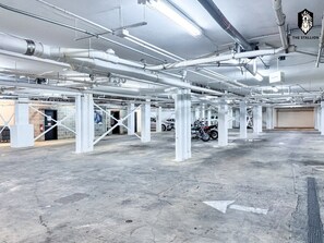 A spacious indoor parking area with concrete floors and white structural supports.