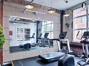 A gym with treadmills, a mirrored wall, and a large window.