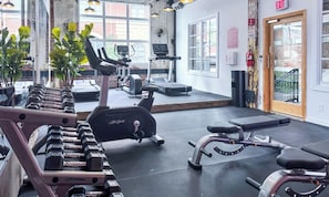 Uma academia com equipamentos de exercício, janelas amplas e sinal de saída.