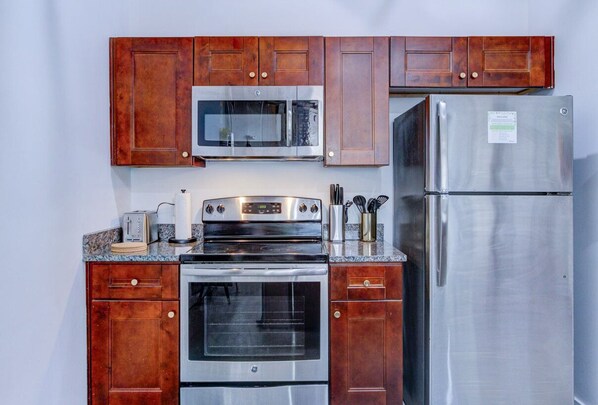 Une cuisine avec des meubles en bois, un four à micro-ondes, un four et un réfrigérateur en acier inoxydable.