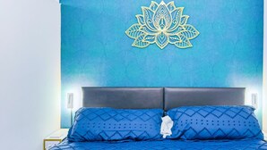 Un lit avec une couvre-lit matelassée bleue et deux oreillers, une tête de lit et un mur orné d’un motif géométrique.