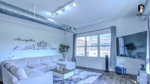A modern living room with a sofa, coffee table, and a cityscape mural.