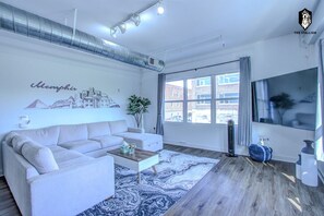 A modern living room with a sofa, coffee table, and a cityscape mural.