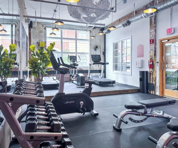 A gym with exercise equipment, a treadmill, and a mirrored wall.