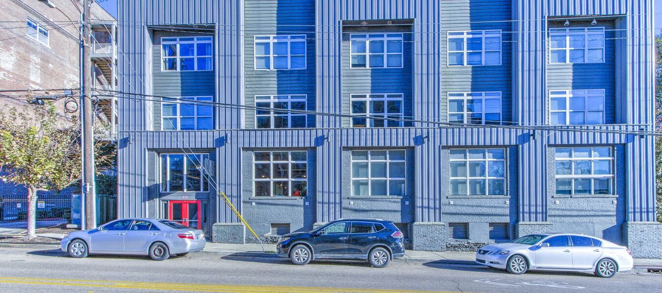 Un edificio de varios pisos con un diseño arquitectónico moderno, que presenta una serie de ventanas y una entrada visible.