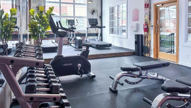 A gym with exercise equipment, a treadmill, and dumbbells. - Walk to Attractions Modern Loft with Private Patio (Memphis)