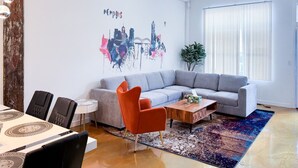 A modern living room with a gray sectional sofa, a wooden coffee table, and a vibrant rug. - Walk to Attractions Modern Loft with Private Patio (Memphis)