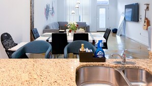 A modern kitchen with granite countertops, a built-in sink, and a dining area with a table and chairs. - Walk to Attractions Modern Loft with Private Patio (Memphis)