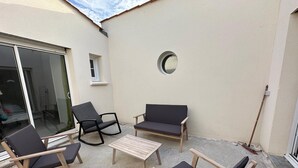 A patio with a table and four chairs, a small window, and a round mirror on the wall. - Splendid house in a peaceful setting (Nieul-sur-Mer)