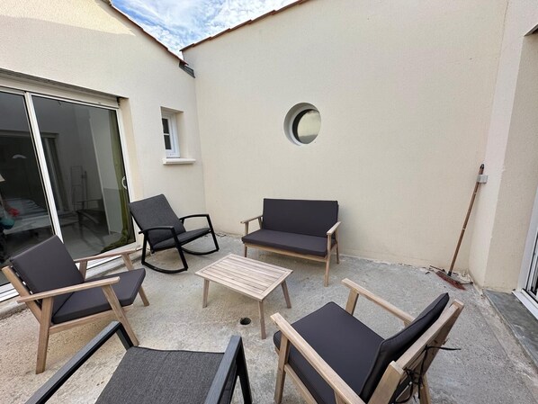 A patio with a table and four chairs, a small window, and a round mirror on the wall. - Splendid house in a peaceful setting (Nieul-sur-Mer)