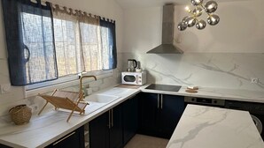 A modern kitchen with a white countertop, dark cabinets, a built-in oven, and a stainless steel range hood. - Splendid house in a peaceful setting (Nieul-sur-Mer)