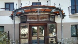 A hotel entrance with a decorative archway, glass doors, and a stone wall. - HOTEL LA FAYETTE LICOLA (Giugliano in Campania)