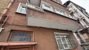 Ein Gebäude mit einem Schild, auf dem 'UMUT APT' steht, und einer Tür mit einem dekorativen Metallgitter.