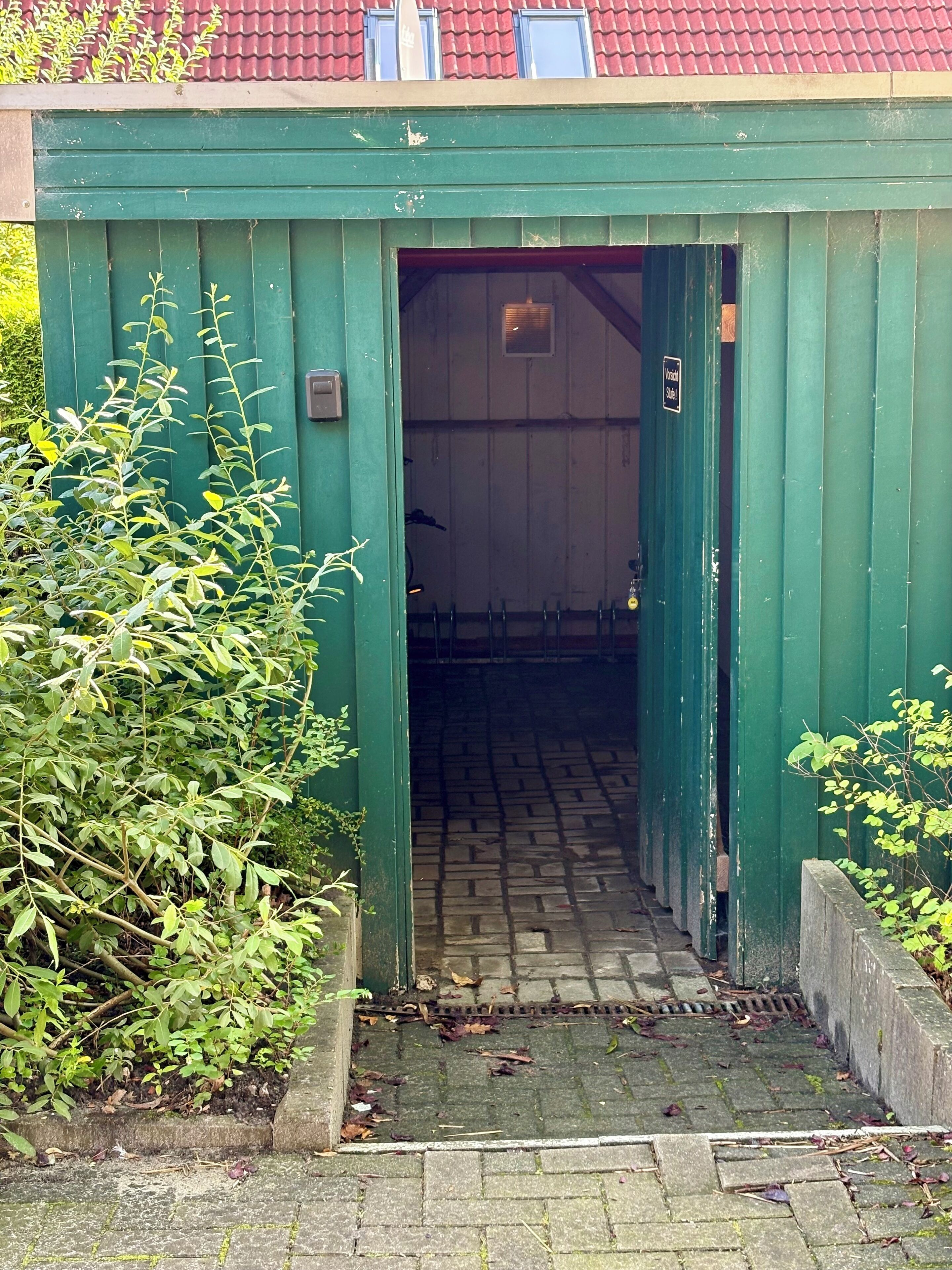 A narrow entrance to a building with a green exterior and a tiled floor.