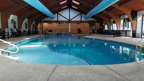Une grande piscine intérieure dotée d’un plafond en voûte et de poutres en bois.