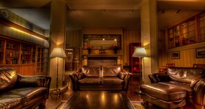 Un salon chaleureux avec des canapés en cuir, une cheminée, des étagères et des lampes.