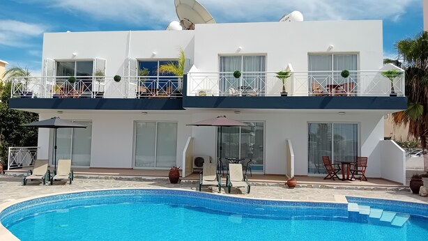 A two-story building with a swimming pool, outdoor seating, and satellite dishes. - Kato Paphos Suites - GF Studio Apartment. Pool View, Wi-Fi, a/c. Great Location (Pafos)