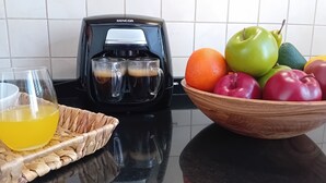 A kitchen counter with a coffee maker, a glass of orange juice, and a bowl of fruit. - Kato Paphos Suites - GF Studio Apartment. Pool View, Wi-Fi, a/c. Great Location (Pafos)