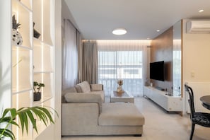 Ein modernes Wohnzimmer mit einer Couch, einem Couchtisch und einem Fernseher.