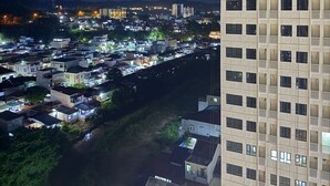 Un immeuble de grande hauteur, doté de nombreux étages et de balcons, qui surplombe une zone densément peuplée, avec divers bâtiments et une rivière.