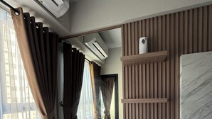 Une chambre moderne avec un lit, des étagères intégrées, un miroir et un appareil de climatisation.