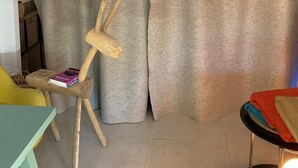 A room with a grey curtain, a wooden chair, a small table, and a staircase. - Large studio with garden: a haven of freshness and greenery right in the center of town (Cavalaire-sur-Mer)