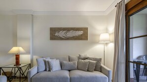 A living room with a sofa, a lamp, a wall art piece, and a window with curtains. - Apartment for 6 in Isla Canela (Ayamonte)