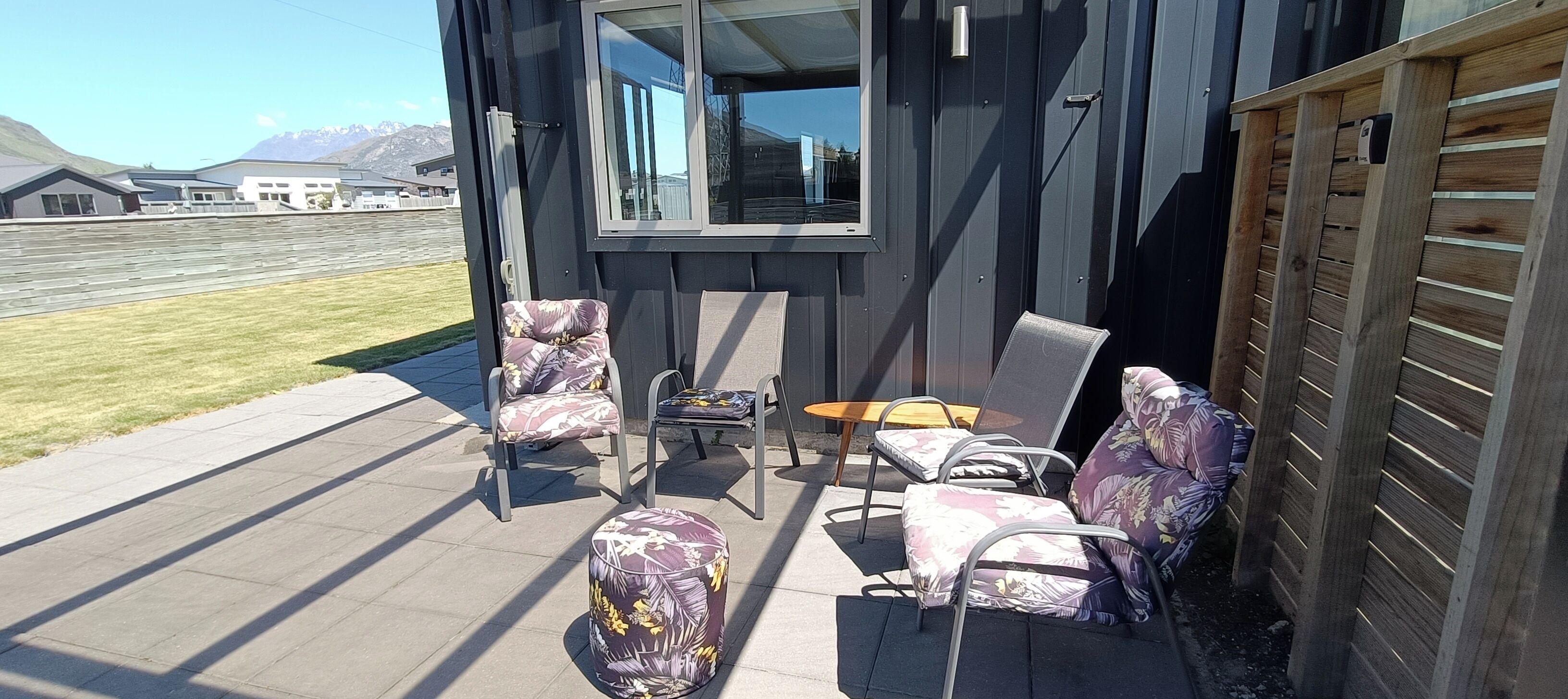 A patio with outdoor furniture, including chairs and a table, and a view of a mountain range in the background.