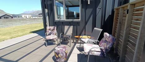 A patio with outdoor furniture, including chairs and a table, and a view of a mountain range in the background.