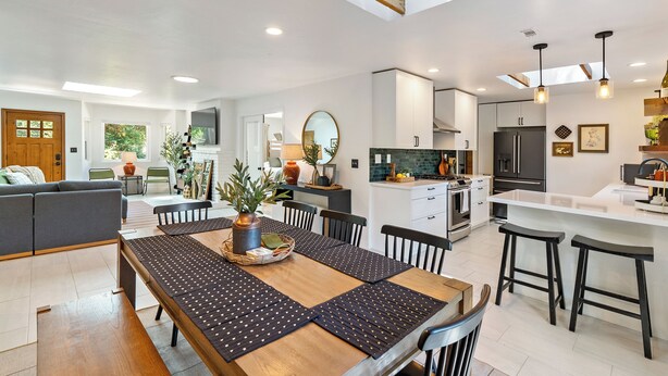 A modern kitchen with a central island, white cabinetry, and a dining area with a wooden table and black chairs. - 15 miles to SLO and PASO-Great Atascadero Home! (Atascadero)