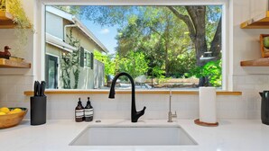 A kitchen with a large window, a black faucet, a wooden bowl with lemons, and two bottles of olive oil. - 15 miles to SLO and PASO-Great Atascadero Home! (Atascadero)