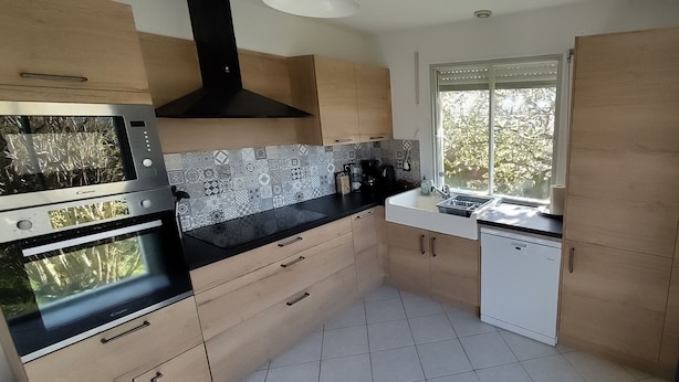 Uma cozinha moderna com armários de madeira, bancada preta e janela que oferece luz natural.