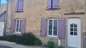 A two-story building with a beige facade, multiple windows with purple shutters, and a white door with the number 26.