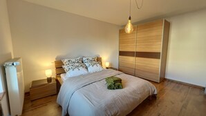 A bedroom with a bed, nightstands, a wardrobe, and a hanging light fixture.
