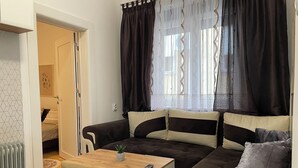 A modern living room with a sofa, a small table, and a radiator. - Cozy & Stylish Townhouse in Central Niš w/ 2BR • WiFi • AC (Niš)