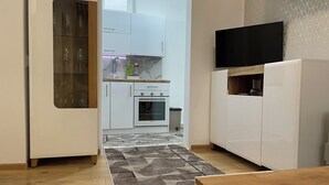 A modern kitchen with white cabinets, a built-in oven, and a TV mounted on the wall. - Cozy & Stylish Townhouse in Central Niš w/ 2BR • WiFi • AC (Niš)