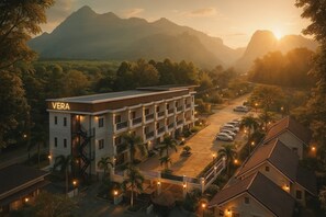 Un hôtel à plusieurs étages, reconnaissable à son grand panneau lumineux «VERA», entouré d’une végétation luxuriante et avec des montagnes en toile de fond.
